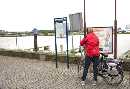woman looking at information board near the river maas in Hollandの写真素材