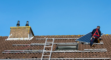 man putting the solar panel to the metal construction on the roofのeditorial素材