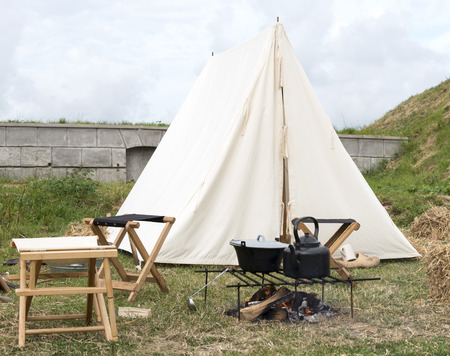 camping with tent and cooking equipment on campfireの写真素材