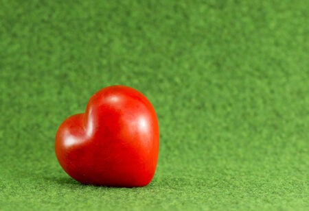 red heart from stone on green backgroundの写真素材
