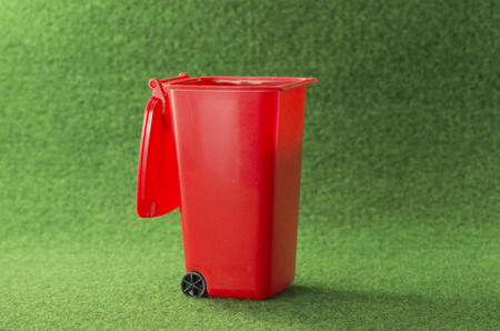 red open garbage bin container on green backgroundの写真素材