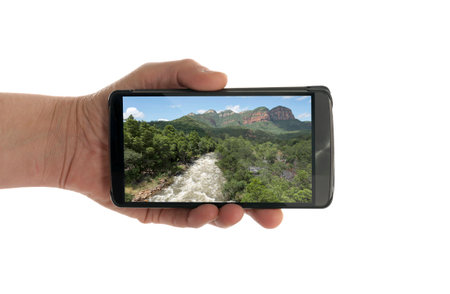female hand with mobile phone isolated on white with drakensberg natureの写真素材