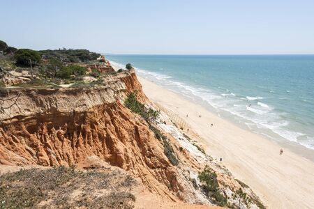 Cliffs at Praia da Falesia near villamoura in portugal area algarve with people walking at the beachの写真素材