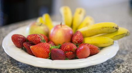 strawberries and banana with two appels on food plateの写真素材