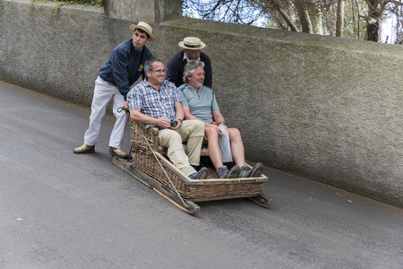 FUNCHAL,PORTUGAL-MARCH 19 Toboggan riders  dive with sledge with tourists on MArch 19, 2016 in Monte- Funchal, Portugal. This is done on public streets and is an old tradition only of this islandのeditorial素材