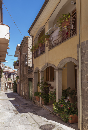 small street in Orgonsolo Sardinia with plants and flowers in the street and windows with shutters and balconies,orgonsolo is famous because of the murales, the wall paintingsのeditorial素材