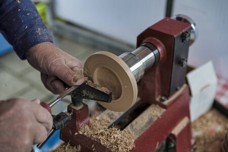 man turning wooden candle stands with a chisel on a wood lathe