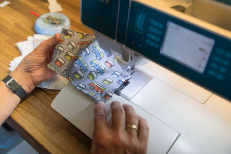 Amsterdam,Holland,15-may-2020:Woman busy with production of home made face corona masks with bus decoration,form now on the mask need to be used in public transportのeditorial素材