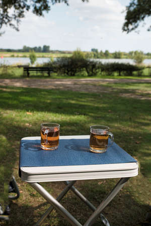two glasses of tea during afternoon break outside on a table on the river Maasの写真素材