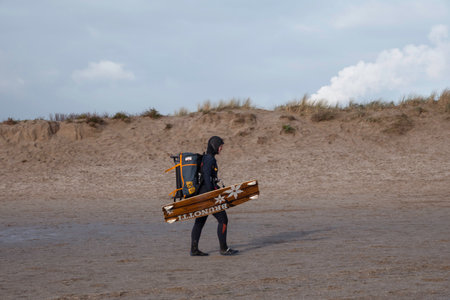 Oostvoorne:Holland,17-jan-2021:Woman with waveboard walking on the beach of oostvoorne, this is a popular palce for watersportsのeditorial素材