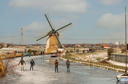 Schipluiden,Holland,14-feb-2021:people skating on the canal near the windmill, it has been years ago that is was so cold in Holland, people can skateのeditorial素材