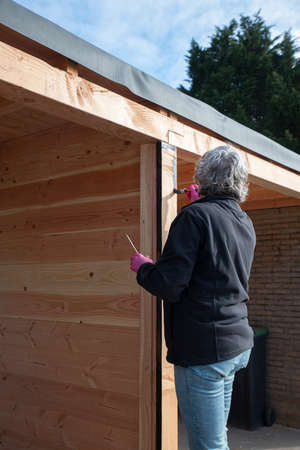 woman painting woorden pole outdoorの写真素材