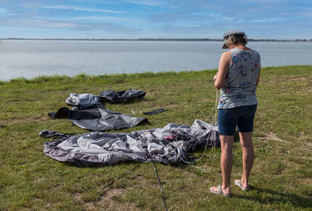adult woman setting up a tent at the waterの写真素材