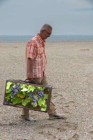 man with old suitcase with garden full of grpes as conceptの写真素材