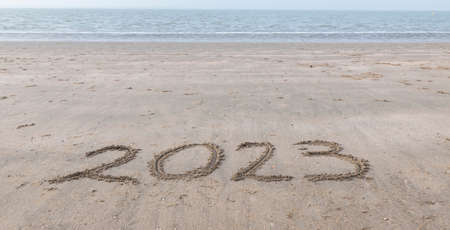 the text 2023 written in the sand on the beach