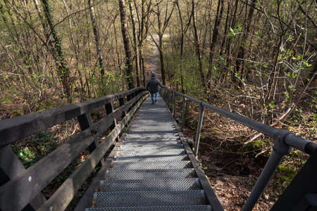 adult woman walks down a large metal staircase in the forest