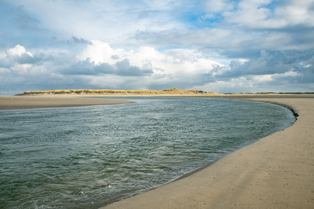 dark clouds over the sea with sunshine on the dunes near the beachの写真素材