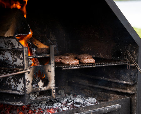 grilling meat on a wood fired barbecue with an open fireの写真素材