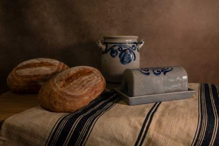 the still life on a beautiful canvas with a butter dish and two loaves of breadの写真素材