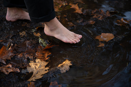 a puddle of rain in the forest with a womans bare feet