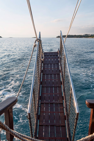 a brown wooden gangway with railing while sailing on the oceanの写真素材