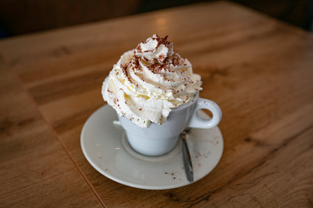 a large cup of cappuccino with lots of whipped cream and chocolate served in a cup in a restaurantの写真素材