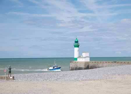 Le Treport lighthouse Seine Maritime, Normandy, France with the beach as foreground and a fishing boat and a man on the leftの写真素材