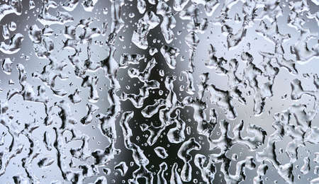 Texture of frozen water drops on the glass. Dark triangle silhouette on the background. High quality...