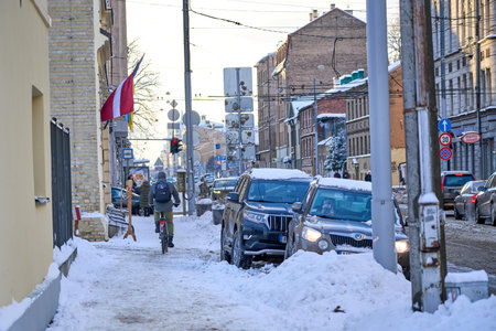 Riga, Latvia - 8 December, 2022: cyclist rides on a snow-covered sidewalk in the city winterのeditorial素材