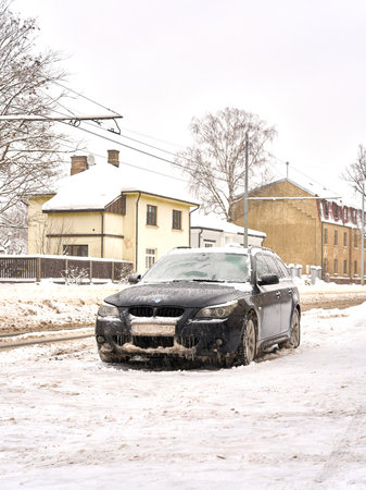 Riga, Latvia - 13 December, 2022: Frozen BMW car covered with ice layer in winter day parked on the street of city. Vertical shot.のeditorial素材