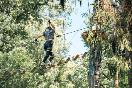 A woman skillfully navigating a challenging tree climbing course while surrounded by vibrant and lush greeneryの写真素材