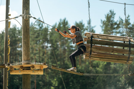 A woman navigates a thrilling rope course, showcasing balance and agility in an outdoor adventure park.の写真素材