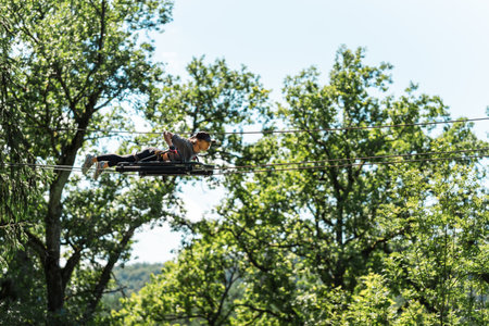 A person is ziplining joyfully through lush greenery, showcasing a thrilling adventure and enjoyable outdoor funの写真素材