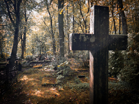 A peaceful autumn cemetery scene features a weathered wooden cross surrounded by vibrant and colorful foliageの写真素材
