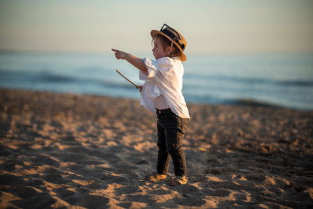 Small baby girl in a hat having fun on Baltic sea beach. She points with finger.の写真素材
