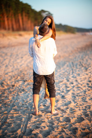 Happy smiling young couple having fun in the sea on holidays. A man holding woman on hands. A man holding woman on handsの写真素材