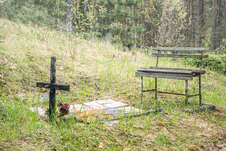 Abandoned grave with old weathered wooden cross and bench at the cemetery. No people.の写真素材