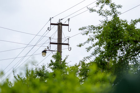 Old electricity power supply pillar. Power line post with electric cables against a clear sky. A...