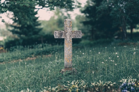 A weathered wooden cross stands in a lush green cemetery, evoking a profound sense of peace and remembranceの写真素材
