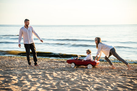 Happy young family having fun on sea shore. Mother, father and daughter on vacation.の写真素材