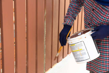 Construction worker is painting wooden fenceの写真素材