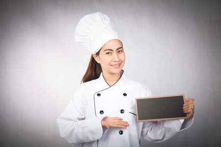 young woman chef holding black board