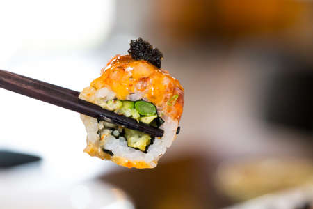 Sushi roll with black chopsticksの写真素材