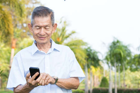 Asian senior man reading message on smartphoneの写真素材