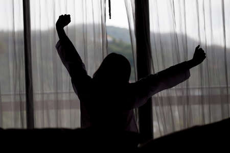 Silhouette of Young asian woman stretching in the morningの写真素材