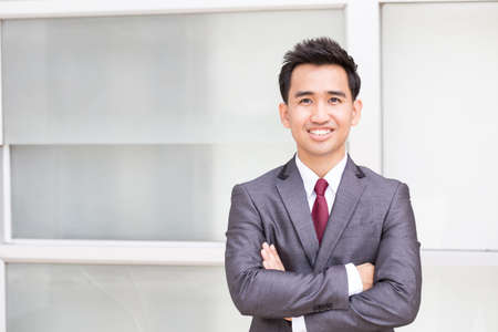 Asian businessman standing arms crossed and smilingの写真素材