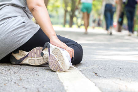 Sports injury. Woman with pain in ankle while joggingの写真素材