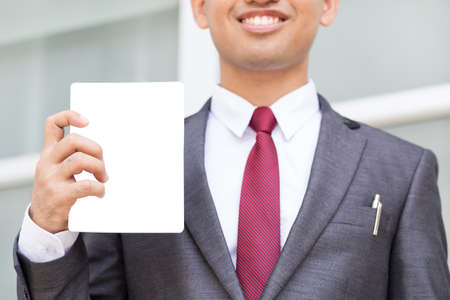 Closeup of torso of asian businessman showing blank paperの写真素材