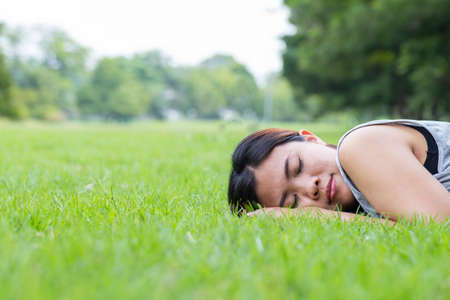 Asian woman sleeping on grass in the parkの写真素材
