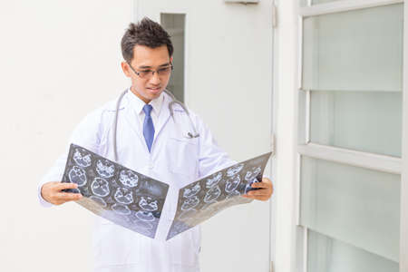 Asian man doctor looking x-ray CT Scan resultsの写真素材